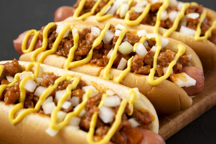 detroit style hot dog also known as the coney dog with beef chili, raw onions and mustard